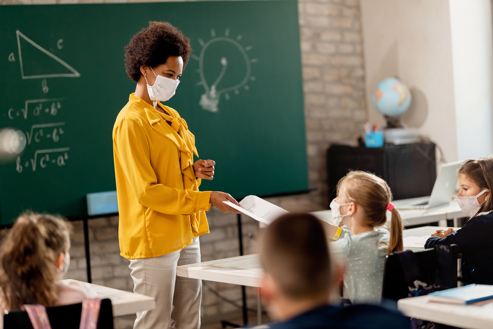 Professora em sala de aula no retorno das aulas presenciais durante a pandemia de COVID-19.